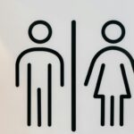 Simple black and white design of unisex restroom signage on a clean surface.