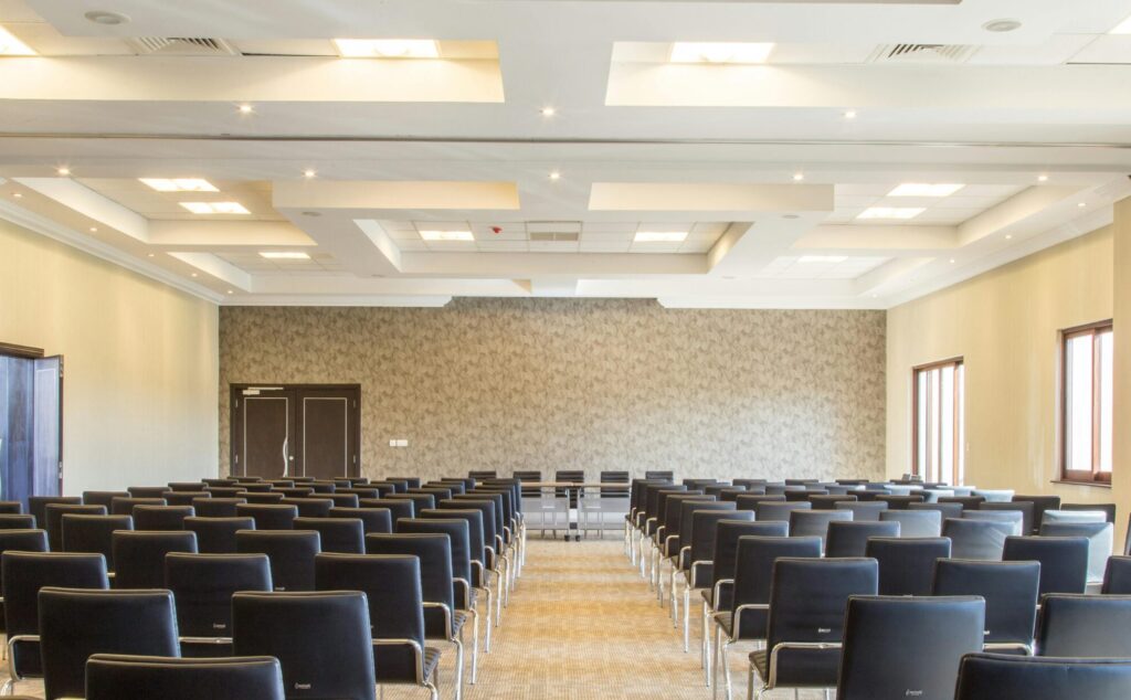 Spacious empty conference room with modern design and neatly arranged black chairs.